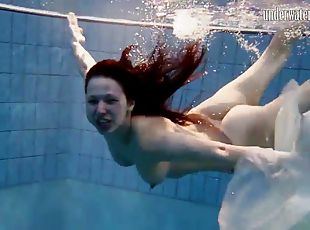 Long hair solo model blonde widening legs while diving in pool