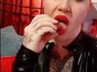 Dominatrix eating a strawberry