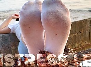 Goddess feet in dirty white socks closeup against sea sunset
